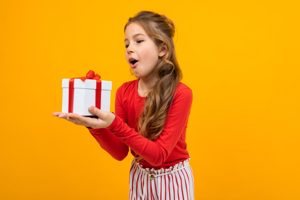白人女孩在一件红色毛衣与一个礼物盒在黄色背景与复制空间图片下载