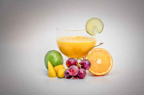 橙汁放在大玻璃杯里，水果放在玻璃杯周围，青柠片放在玻璃杯边缘图片下载