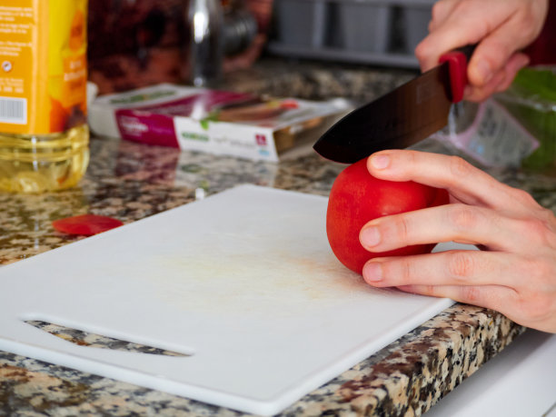 在砧板上切西红柿的方法不对。家乡菜。从花园里摘来的新鲜番茄。在大理石操作台上切西红柿的女人。图片下载