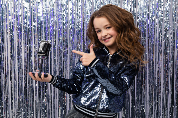 有才华的时尚女孩手拿复古麦克风在一个闪亮的节日背景图片下载