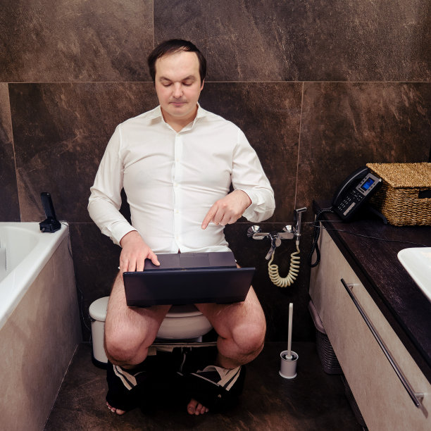 穿着衬衫的快乐男人光着脚坐在家里的马桶上锻炼。在流感大流行期间在家远程工作图片下载