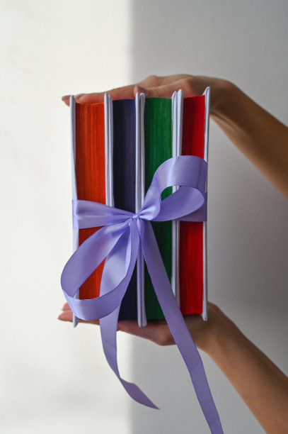 裁剪的观点，妇女拿着书与丝带系在白色的背景与自然的阴影。一本好书是一个好的礼物概念图片下载