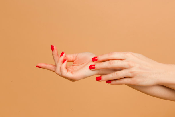 近距离照片的女人享受她的美丽。迷人的手与美甲的年轻女子孤立在米色背景。图片下载