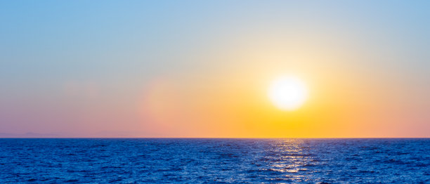 海面上的橙色日落：沐浴在阳光下的海平面，享受浪漫假期图片下载