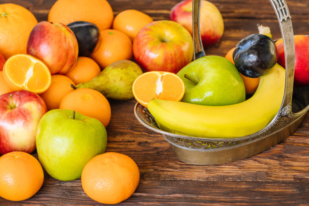 木制背景上的健康水果。时尚，华丽的金属篮子里装满了新鲜水果。适当的营养概念，富含维生素图片下载