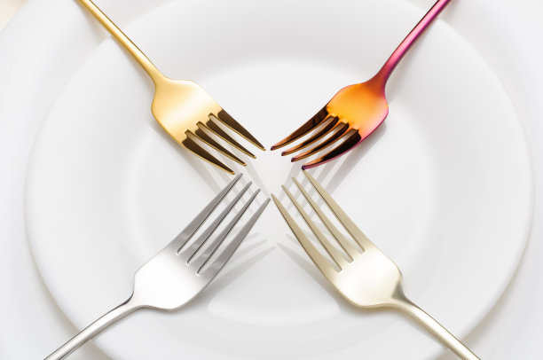 白色盘子上有创意的彩色金属叉子图片下载