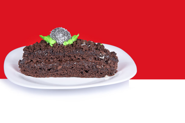 白色盘子上的棕色蛋糕。红色背景上孤立的甜饼干，自制布朗尼。图片下载