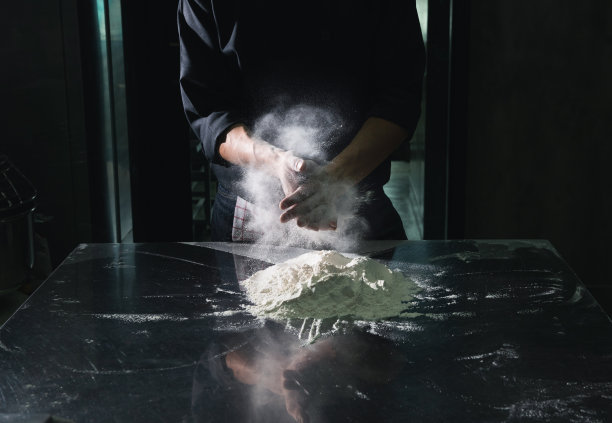 厨师用白粉掸人的手拍了拍黑色的背景图片下载