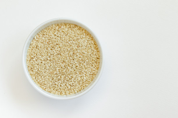 在一个玻璃碗芝麻，孤立在白色的背景。前视图。图片下载