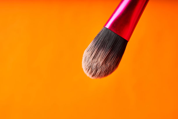 化妆刷在橙色的背景。美容手术工具图片下载