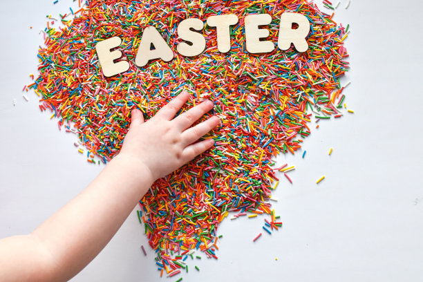 一个孩子的手伸向复活节这个词。用于糖果产品。图片下载