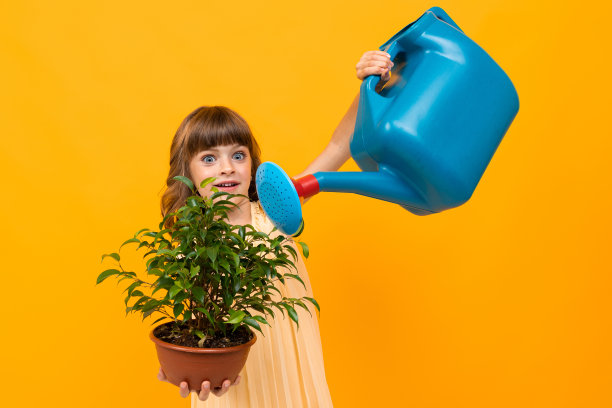 漂亮的小女孩穿着衣服浇一朵孤立在黄色和橙色背景上的花图片下载