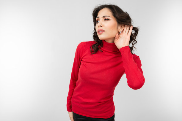 一个身穿红色毛衣的黑发女孩手抓着耳朵，仔细地听着录音室的白色背景图片下载