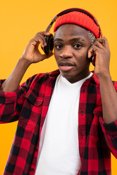 穿着红色格子衬衫的非洲人戴着耳机听音乐图片下载