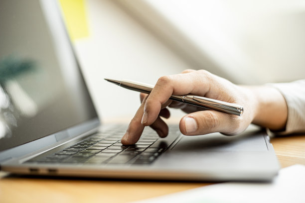 这是一张特写照片，一位商人在笔记本电脑上打字，检查公司的财务文件，这些文件是财务部为与业务伙伴开会准备的。金融的概念。图片下载