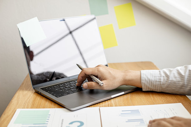 这是一张特写照片，一位商人在笔记本电脑上打字，检查公司的财务文件，这些文件是财务部为与业务伙伴开会准备的。金融的概念。图片下载