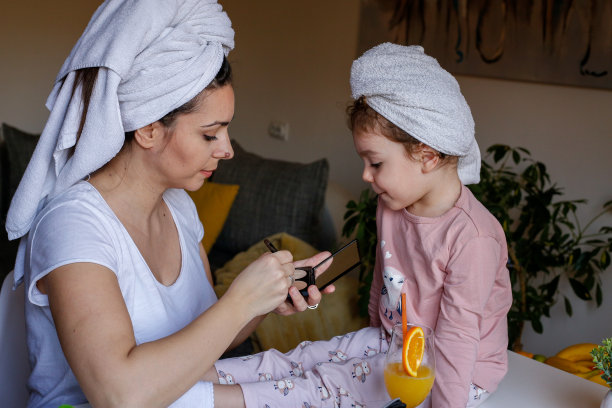 妈妈教小女儿化妆。库存图片图片下载