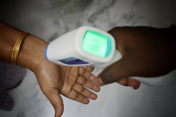 检查体温，预防病毒，预防传染病。用酒精凝胶洗手可杀灭细菌。医用红外体温计使用身体、印度。图片下载