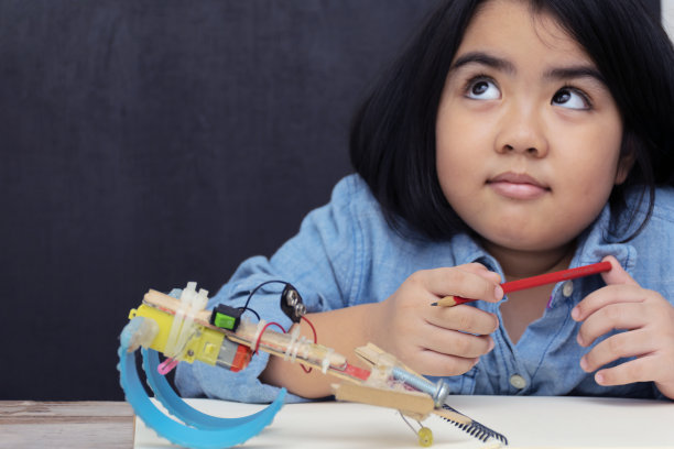 一个可爱的亚洲女孩正在学习组装一个机器人在上课时间，思考。一个学习创新的开始。图片下载