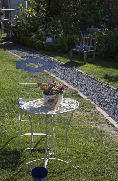 旧金属桌子和椅子在草坪上的花园与人行道图片下载