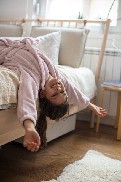 快乐的小女孩躺在床上，穿着浴袍。图片下载