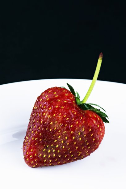 白色盘子上的心型草莓-黑色背景。图片下载