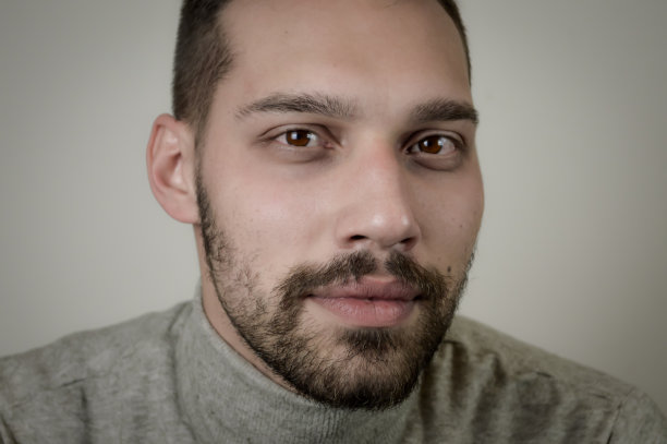 一个年轻的棕色头发，留着短胡子，穿着灰色高领毛衣的男人的肖像图片下载