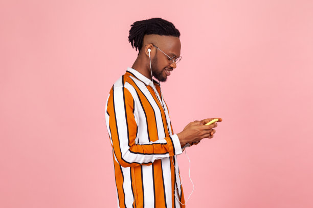 一名穿着条纹衬衫戴着耳机、梳着雷鬼辫的美国黑人在一边听着音乐一边聊天图片下载