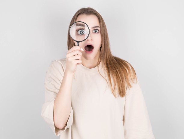 震惊的女人透过放大镜看图片下载
