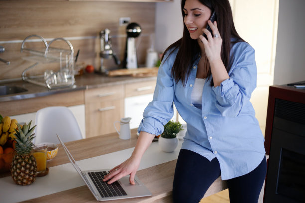 女人用智能手机在厨房库存照片图片下载
