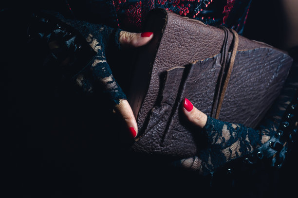 戴着花边手套拿着皮面装订的大部头图片下载