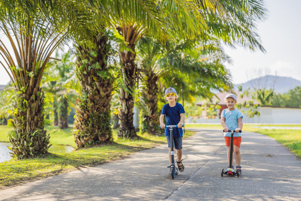男孩和女孩在公园里骑滑板车。孩子们学滑旱冰。小男孩在阳光明媚的夏日滑冰。儿童在安全住宅区街道的户外活动。学龄前儿童的积极运动图片下载