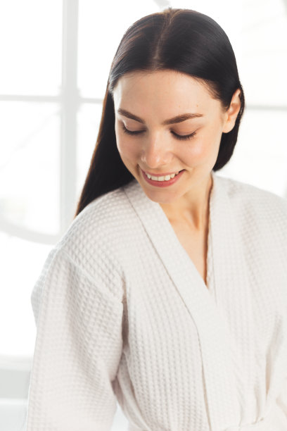 美丽女人洁净健康的皮肤，自然的化妆spa美容概念长黑发。穿白色浴衣的女人图片下载