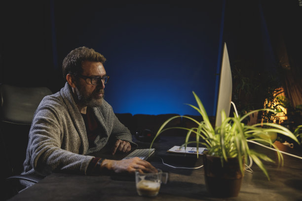 一个成年人深夜在家里的办公室里使用电脑图片下载