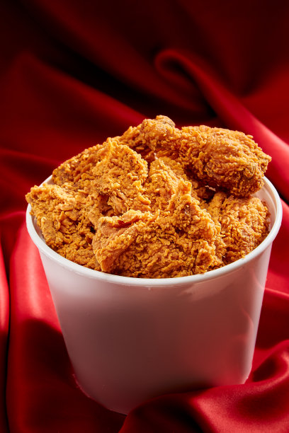 红色奢华绸缎背景下的酥脆炸鸡图片下载