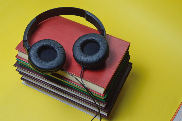 黄色的背景是一堆书和黑色的大耳机。图片下载