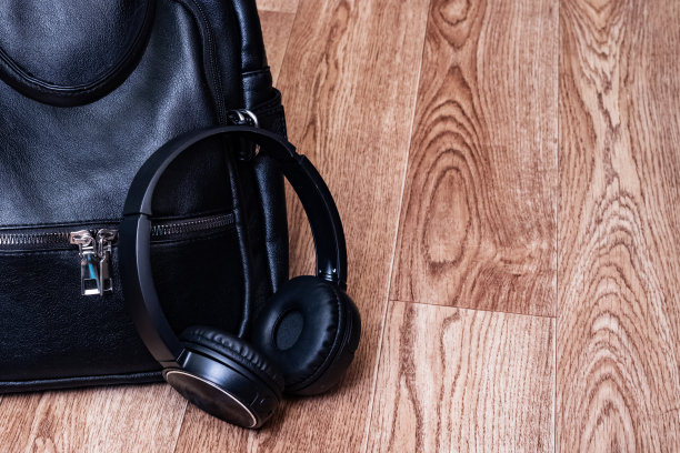 耳机和皮革背包放在木地板上图片下载