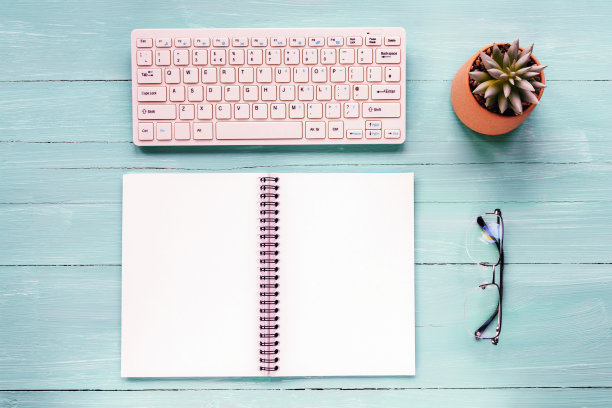 空白的记事本、键盘、眼镜和绿松石木桌上的盆栽。俯视图，平躺，模拟图片下载