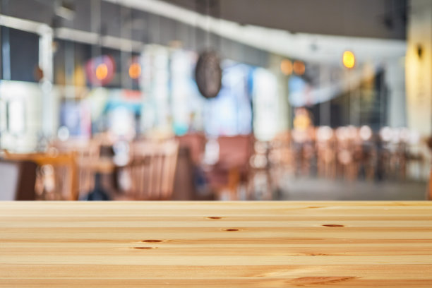 在明亮的日光下，木桌的背景是模糊的现代咖啡馆餐厅内部图片下载