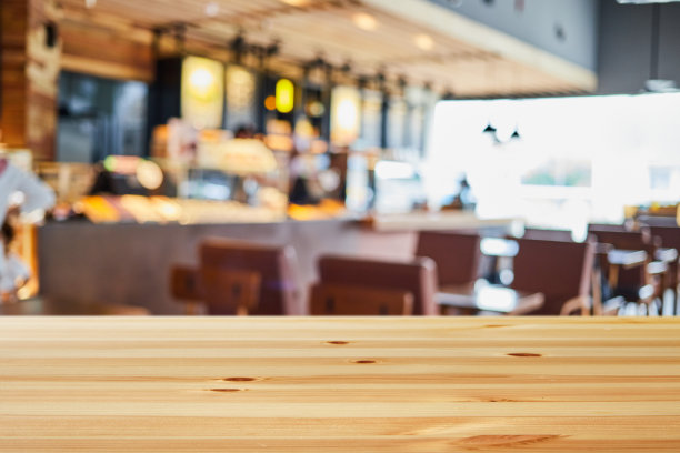 在明亮的日光下，木桌的背景是模糊的现代咖啡馆餐厅内部图片下载