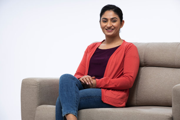 年轻女子坐在白色背景的沙发上图片下载