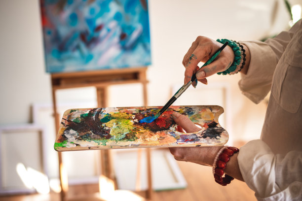 艺术家在调色板上混合丙烯酸颜料，并致力于抽象画图片下载
