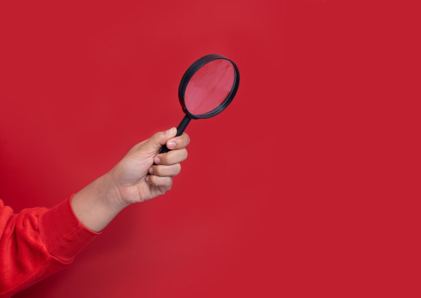 手持放大镜在红色背景上图片下载