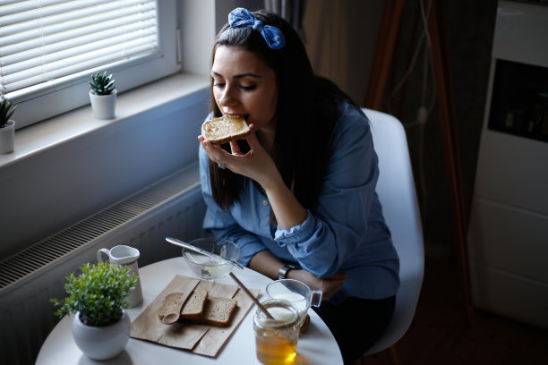 女人在烤面包上吃蜂蜜的照片图片下载
