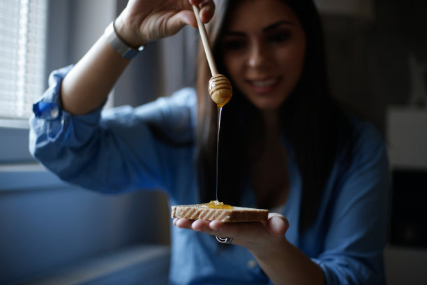 年轻女子准备早餐牛奶和蜂蜜stock照片图片下载