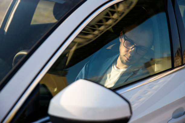 一个疲惫的商人坐在她的车里睡着了，透过挡风玻璃可以看到图片下载