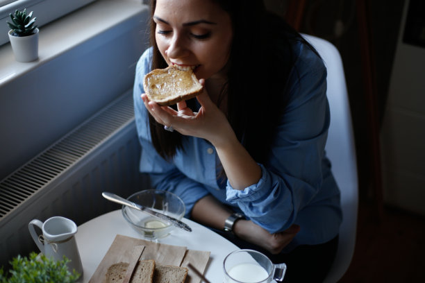 女人在烤面包上吃蜂蜜的照片图片下载