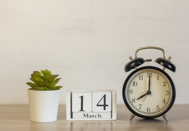 在3月14日的一个木制日历旁边的闹钟。日历日期，节日事件，或生日。图片下载