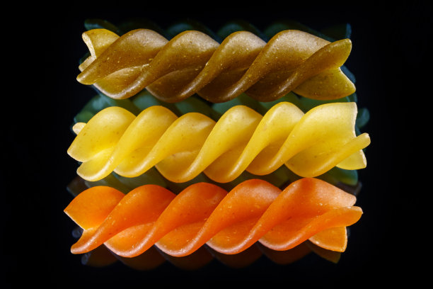 黑色背景上的生三色通心粉。宏观的食物照片。图片下载