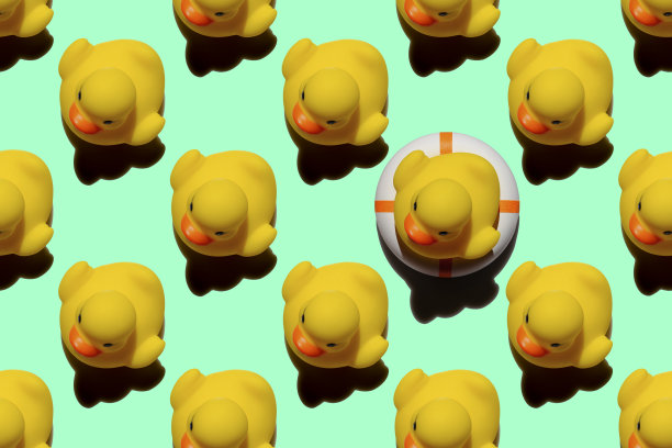 许多黄色橡皮鸭以抽象的形式重复图案，一只黄色橡皮鸭坐在一个充气救生圈上，以绿松石为背景，从人群中脱颖而出。图片下载